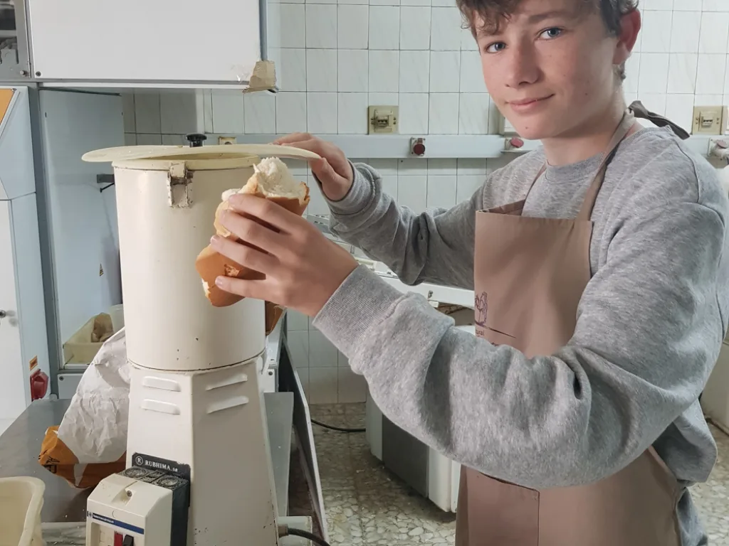 Ein Jugendlicher arbeitet im Praktikum an einer Teigmaschine in der Bäckerei.